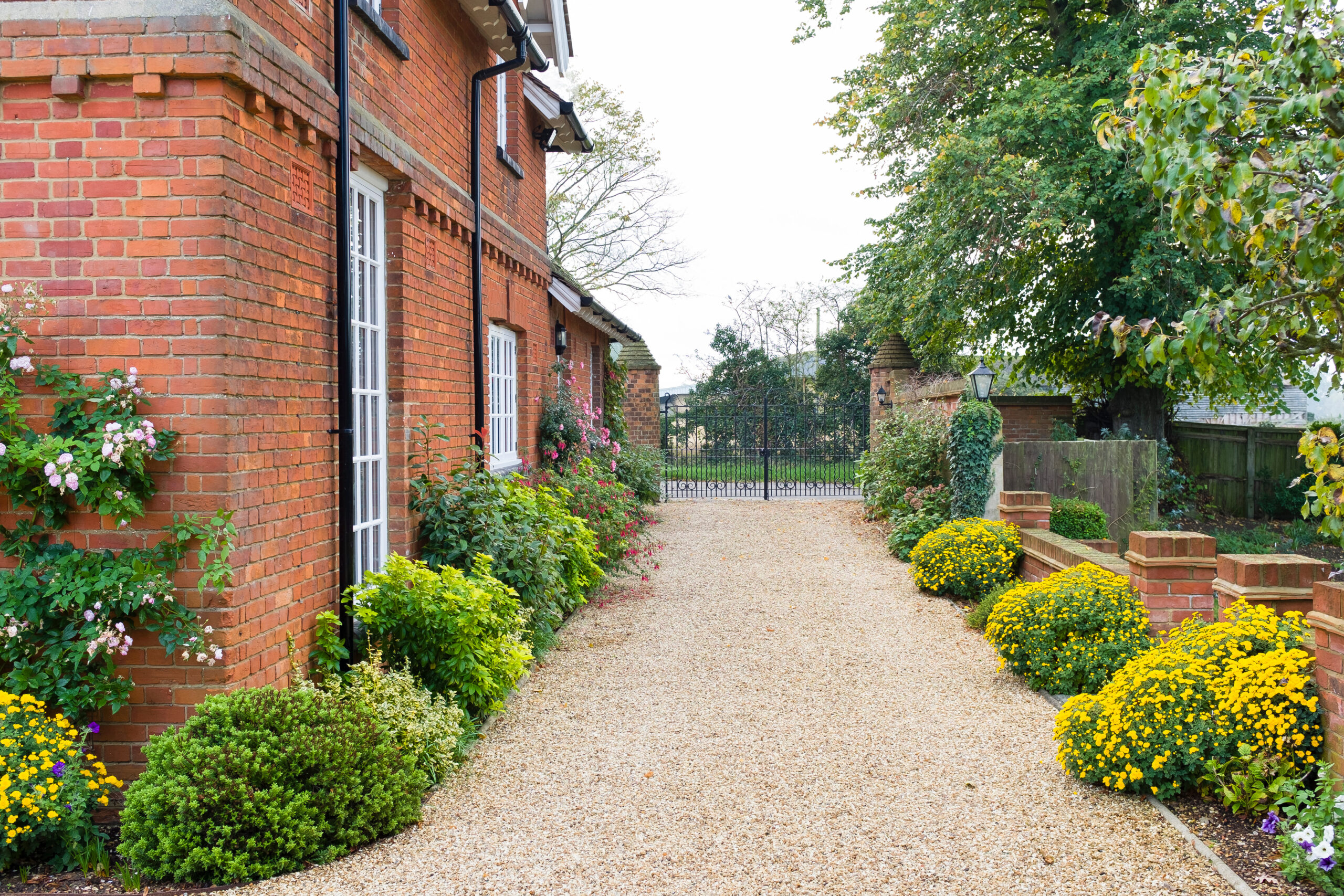 Large English country mansion house from Victorian period in the UK, with wrought iron gates and gravel drive.
